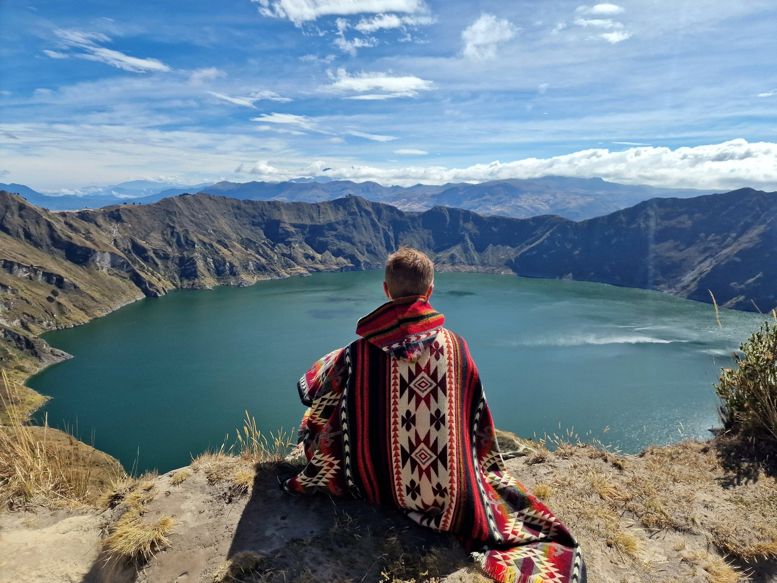 Sitting in a woven poncho above the Quilotoa crater lagoon, Ecuador